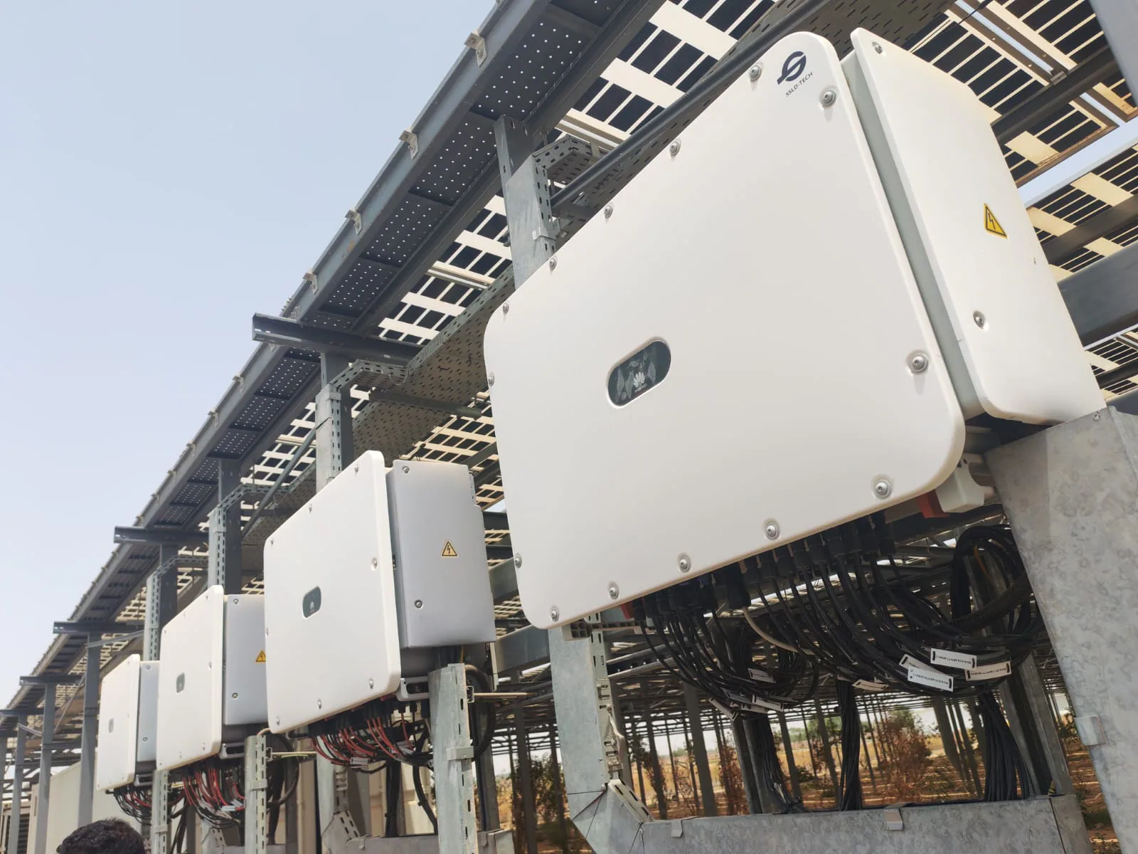 Installed row of solar inverters beneath the PV array at Liwa